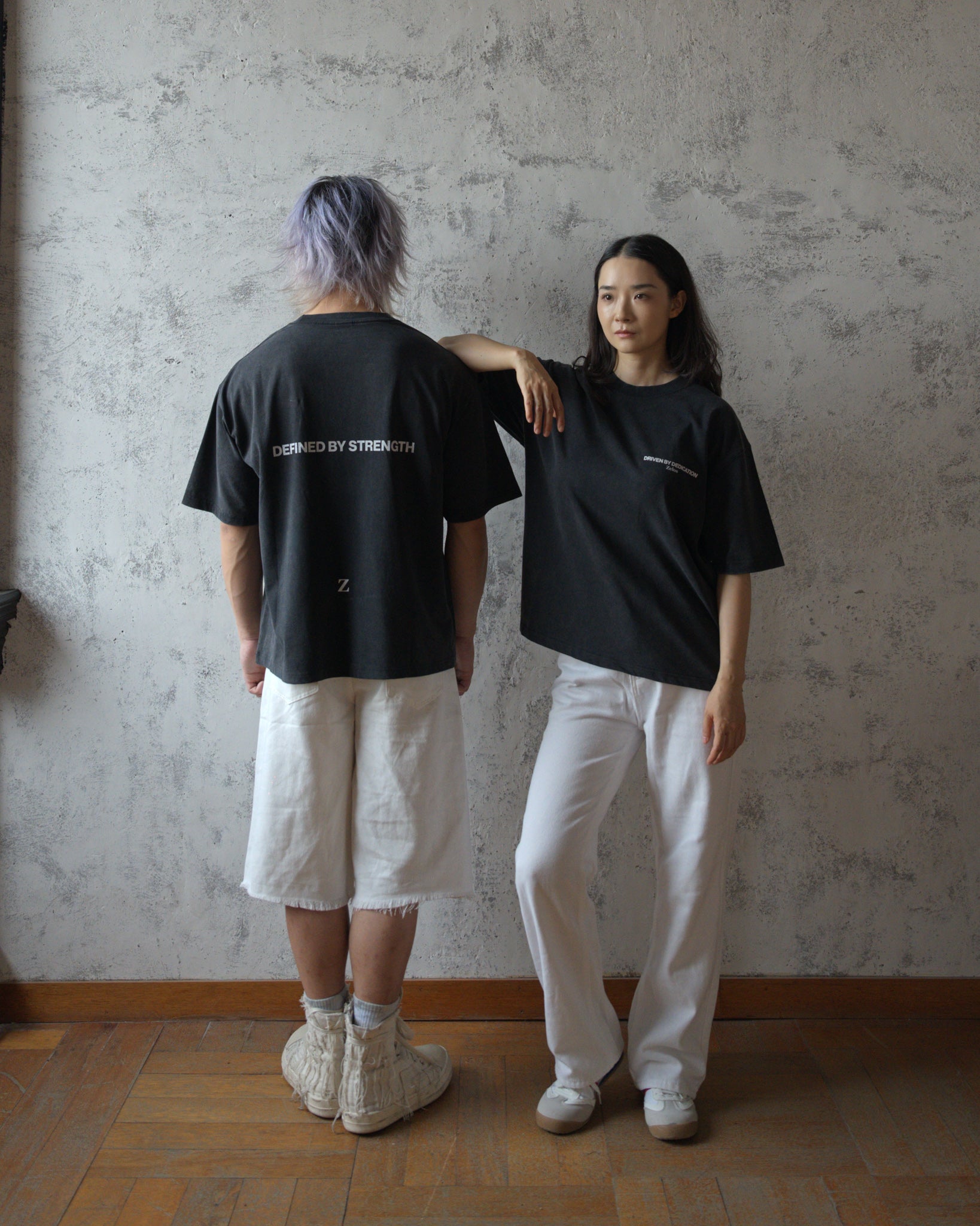 Two models wearing Zelos Tee Black, back and front views