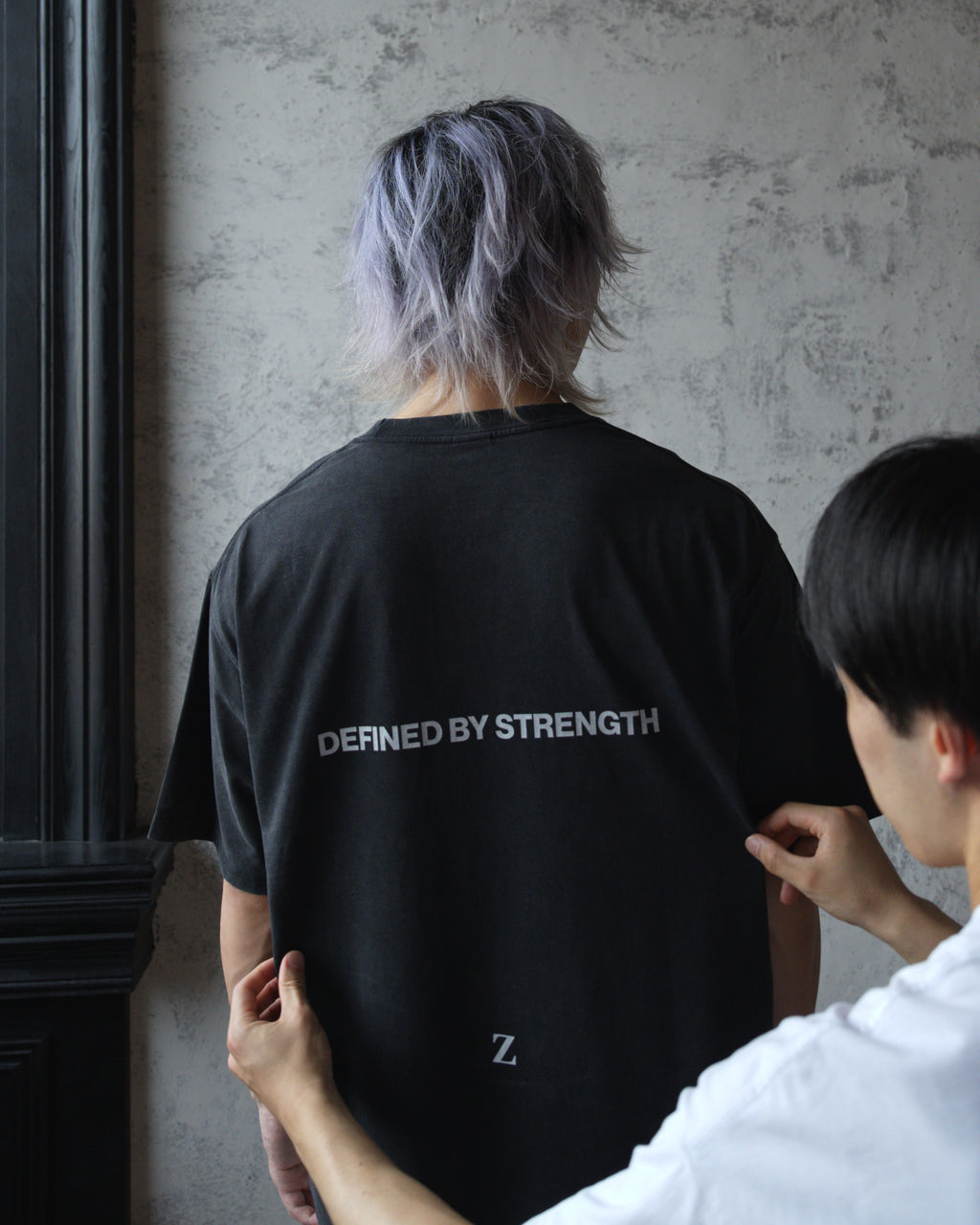 Close-up of Zelos Tee Black back print reading Defined by Strength